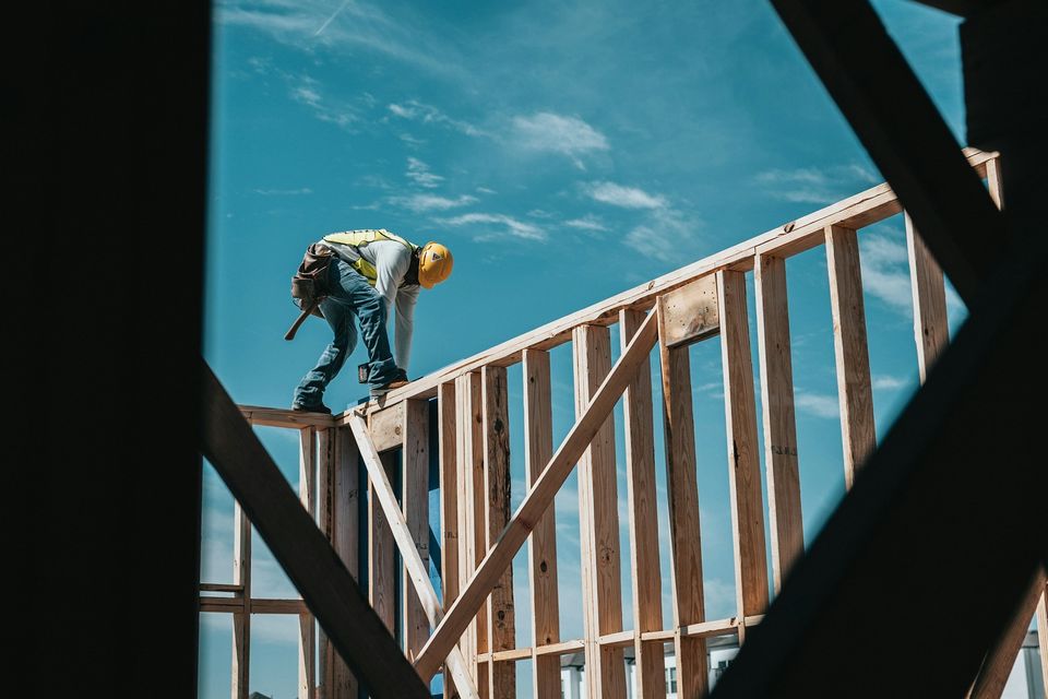 A builder working on top of a wood house frame